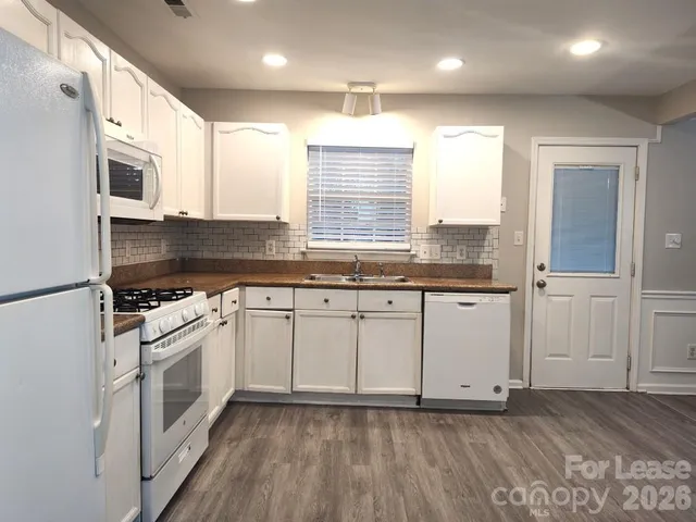 a kitchen with granite countertop white cabinets and white appliances