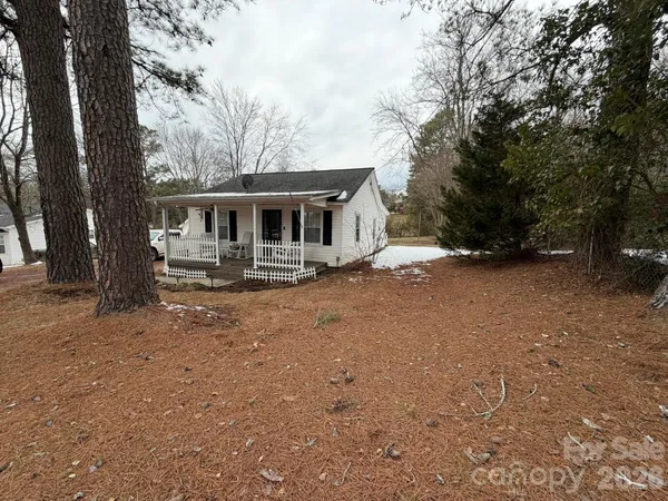 a front view of house with yard and trees in the background