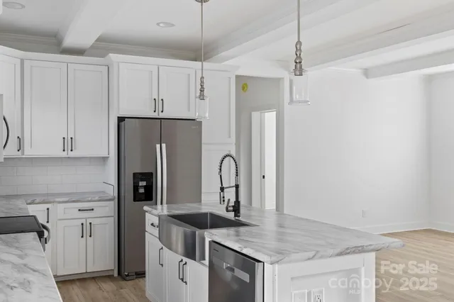 a kitchen with stainless steel appliances granite countertop a refrigerator a sink and white cabinets