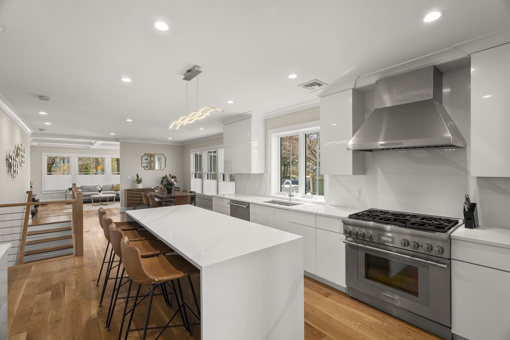 148 Kent Street, Unit 148 Brookline, MA 02446 - Photo 3 of 19 a kitchen with stainless steel appliances kitchen island a table chairs stove and white cabinets