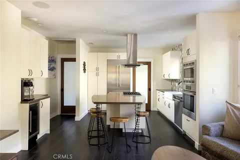 a kitchen with stainless steel appliances kitchen island granite countertop a refrigerator a stove a microwave oven a dining table and chairs with wooden floor