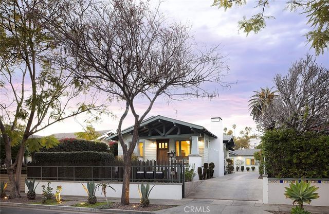 a front view of a house with a tree