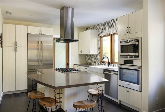 a kitchen with kitchen island stainless steel appliances a stove refrigerator sink and cabinets