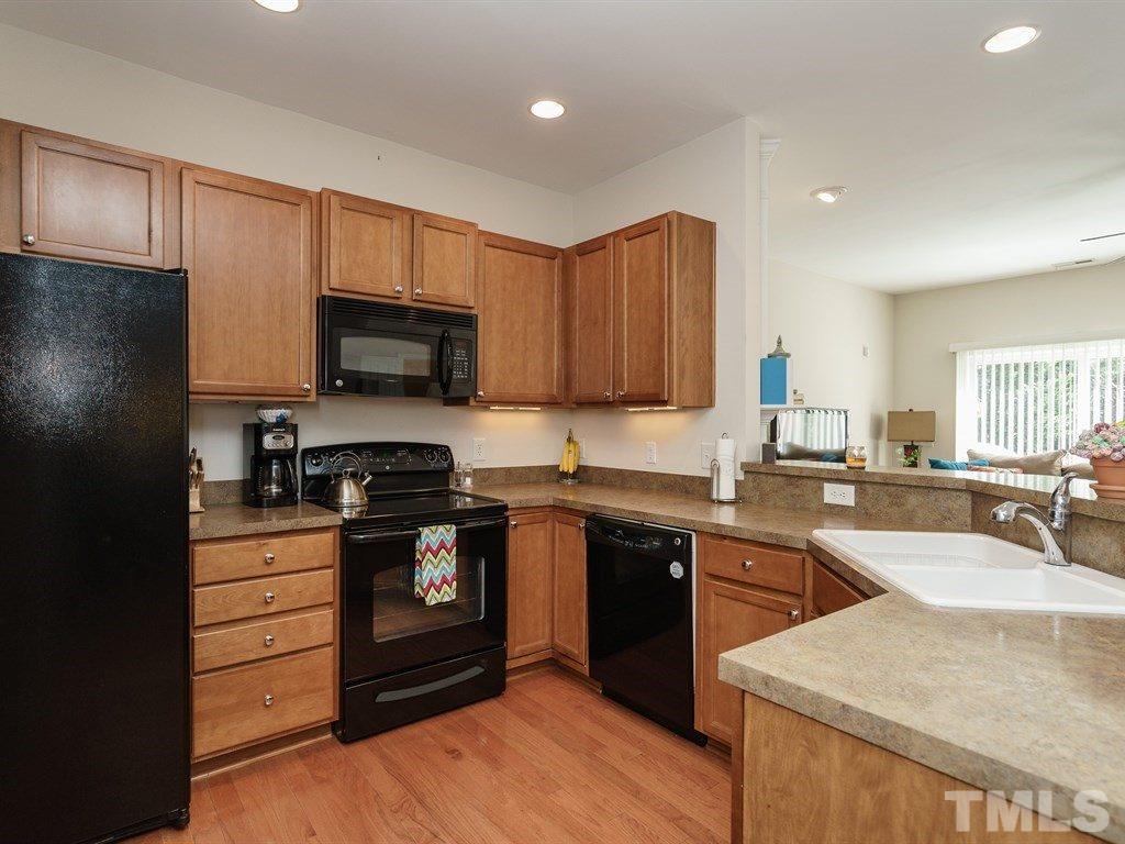 8326 Pilots View Drive Raleigh, NC 27617 - Photo 8 of 25 a kitchen with stainless steel appliances granite countertop a stove top oven a sink dishwasher and a refrigerator with wooden cabinets
