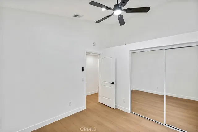 an empty room with closet and a ceiling fan