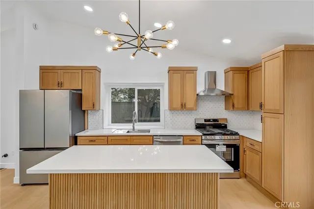 a kitchen with stainless steel appliances kitchen island a stove a refrigerator a sink a dining table and chairs