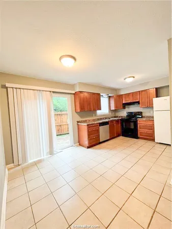 a large kitchen with stainless steel appliances kitchen island granite countertop a refrigerator and a stove top oven
