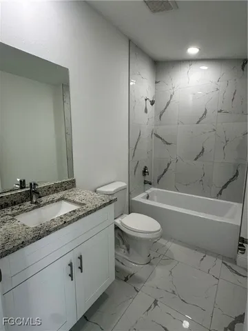a bathroom with a granite countertop sink a toilet and bathtub
