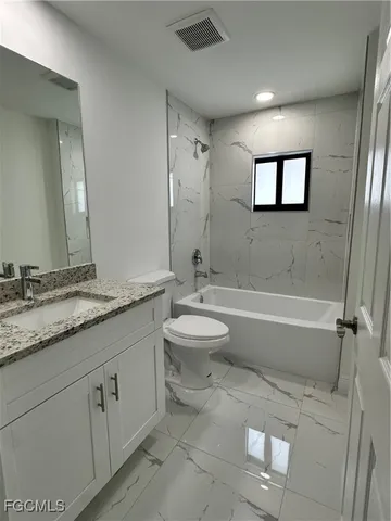 a bathroom with a granite countertop sink mirror toilet and bathtub