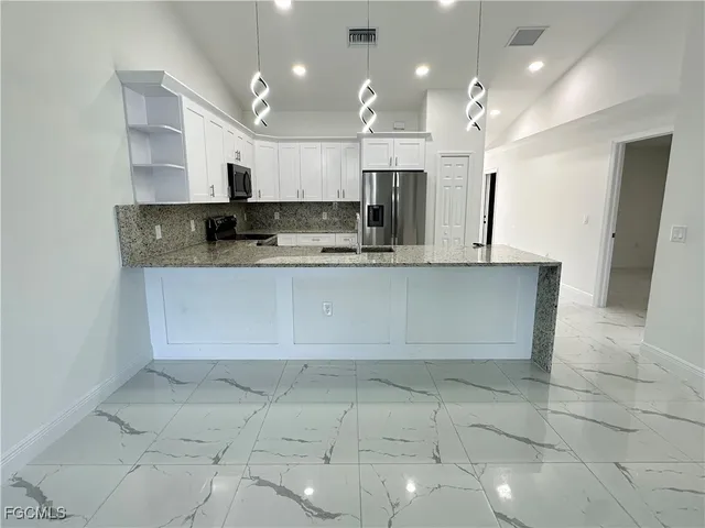 a large kitchen with kitchen island a sink a counter and stainless steel appliances
