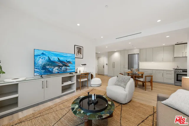 a living room with furniture a rug and kitchen view