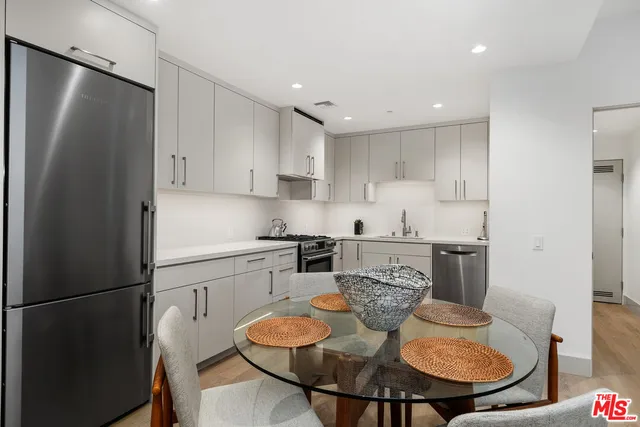 a kitchen with stainless steel appliances granite countertop a refrigerator a sink a stove a dining table and chairs