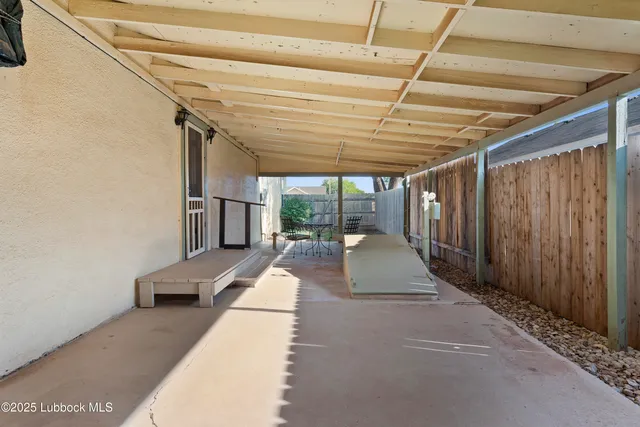 a view of a patio with table and chairs with wooden floor and fence