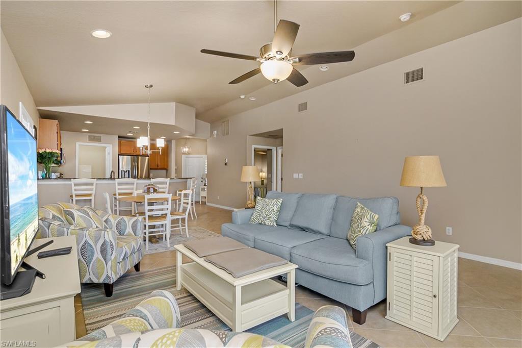 19633 Villa Rosa Loop Estero, FL 33967 - Photo 16 of 50 Living room featuring ceiling fan with notable chandelier, vaulted ceiling, and light tile patterned flooring