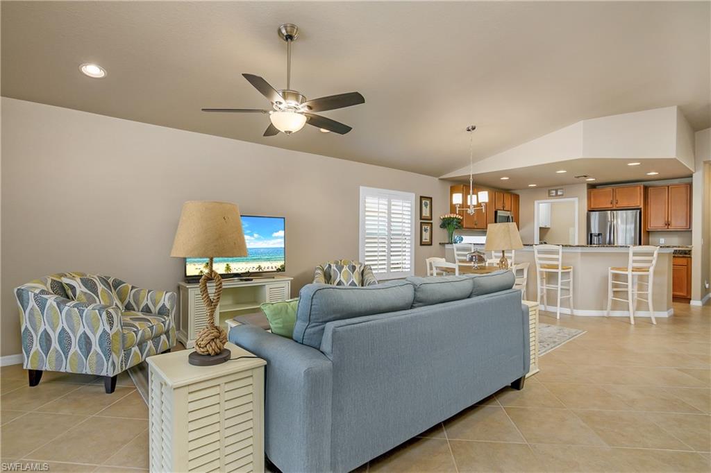 19633 Villa Rosa Loop Estero, FL 33967 - Photo 17 of 50 Living room with ceiling fan with notable chandelier, vaulted ceiling, and light tile patterned flooring
