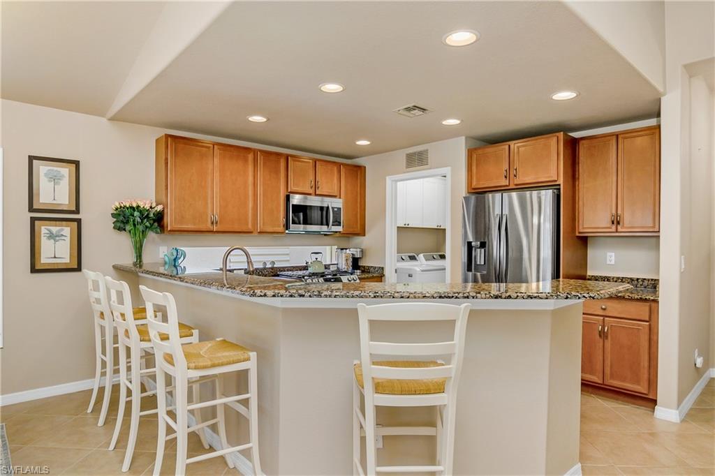 19633 Villa Rosa Loop Estero, FL 33967 - Photo 9 of 50 Kitchen with washer and clothes dryer, light tile patterned floors, appliances with stainless steel finishes, and dark stone counters