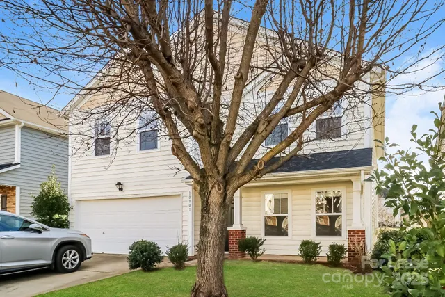 a view of a white house next to a yard with big trees