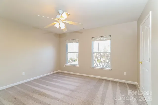 an empty room with windows and fan