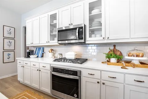 a kitchen with stainless steel appliances granite countertop white cabinets a stove a sink and dishwasher
