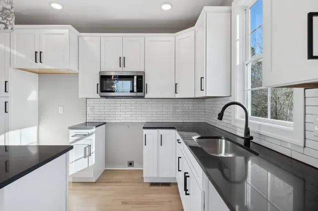 a kitchen with granite countertop white cabinets and stainless steel appliances