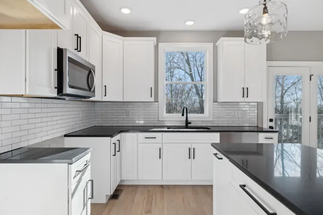 a kitchen with granite countertop a sink white cabinets and stainless steel appliances