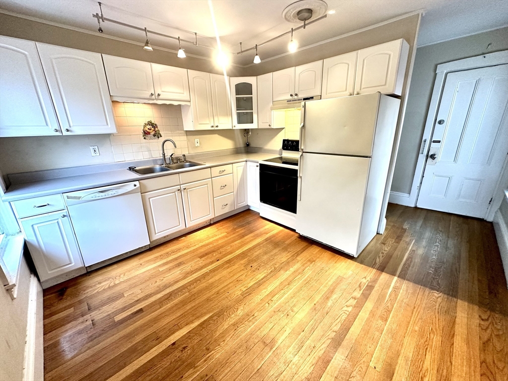 6 Grant Street, Unit 2 Natick, MA 01760 - Photo 4 of 15 a kitchen with granite countertop a refrigerator a sink dishwasher a stove top oven a washer and dryer with wooden floor
