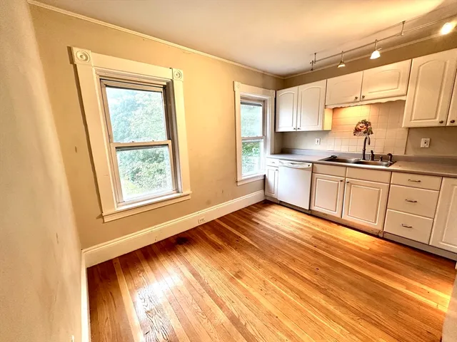 a view of a kitchen with wooden floor and stainless steel appliances