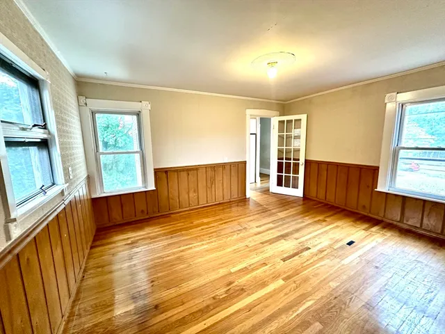 a view of empty room with wooden floor and fan