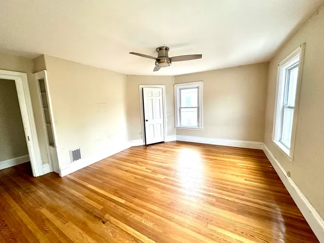 a view of empty room with wooden floor and fan