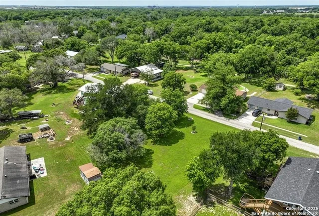 an aerial view of residential houses with outdoor space and trees
