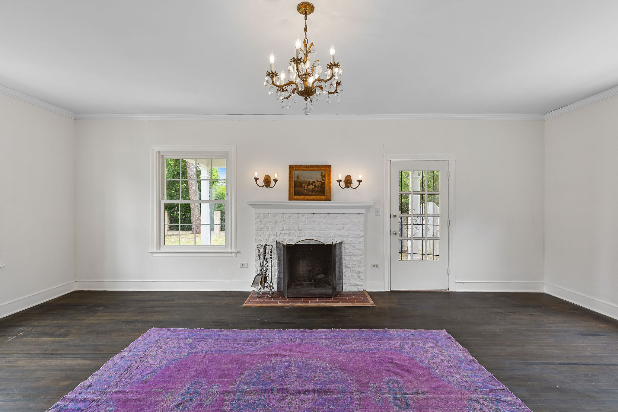 948 Maple Street Lockhart, TX 78644 - Photo 7 of 40 A graceful chandelier illuminates rich dark flooring and a white-painted brick fireplace.