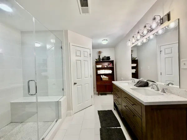 a spacious bathroom with a double vanity sink a large mirror and shower
