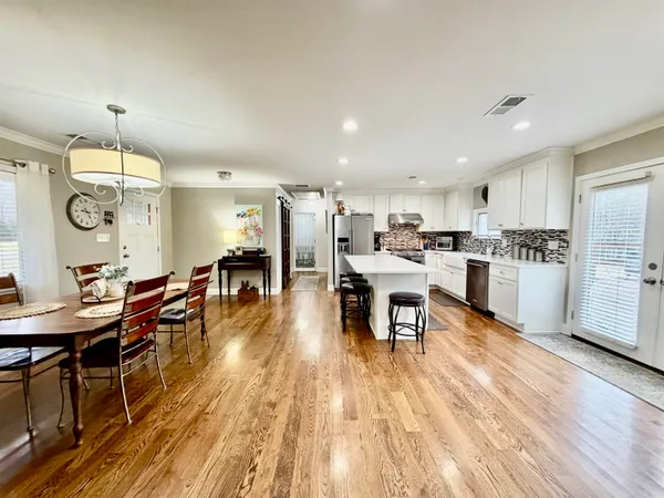 a living room with stainless steel appliances kitchen island granite countertop furniture wooden floor and a view of kitchen