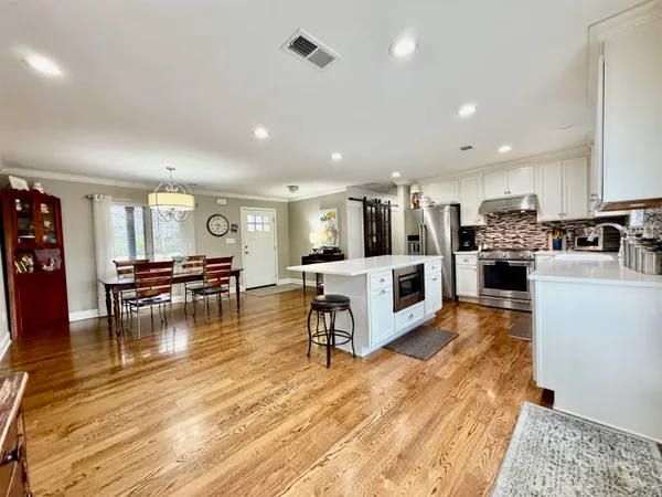 a living room with stainless steel appliances furniture and a wooden floor