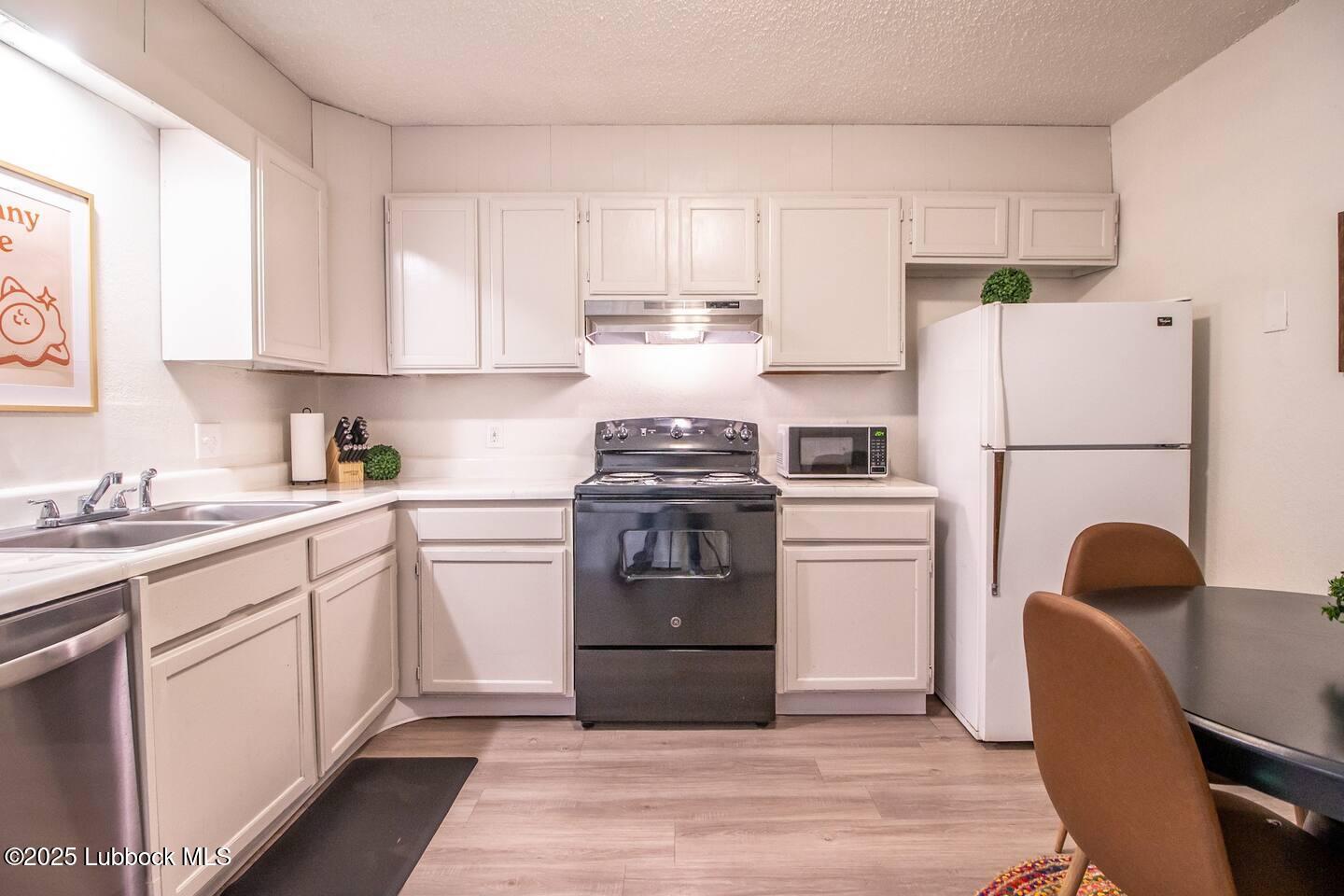 5808 6th Street, Unit B Lubbock, TX 79416 - Photo 7 of 23 a kitchen with a refrigerator stove and white cabinets