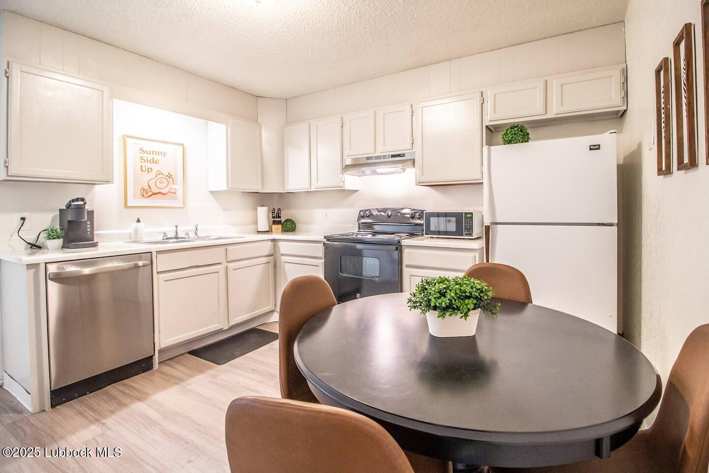 5808 6th Street, Unit B Lubbock, TX 79416 - Photo 8 of 23 a kitchen with stainless steel appliances granite countertop a sink a refrigerator a stove a dining table and chairs