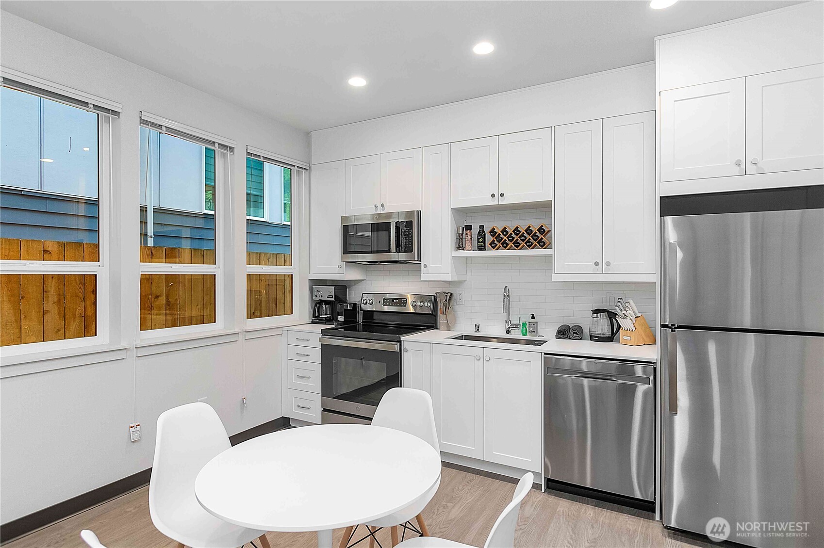 2613 3rd Avenue West Seattle, WA 98119 - Photo 22 of 26 a kitchen with stainless steel appliances granite countertop a refrigerator a stove a sink dishwasher and white cabinets with wooden floor
