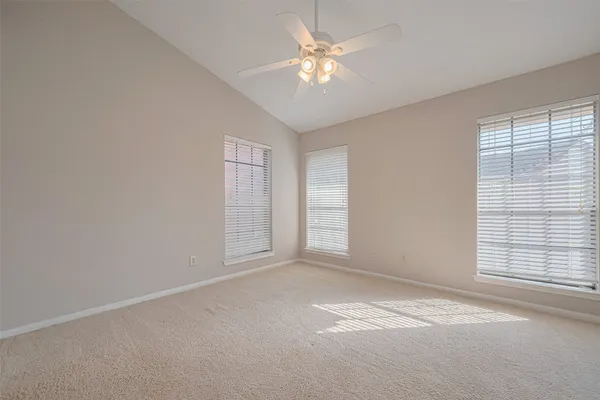 an empty room with windows and chandelier fan