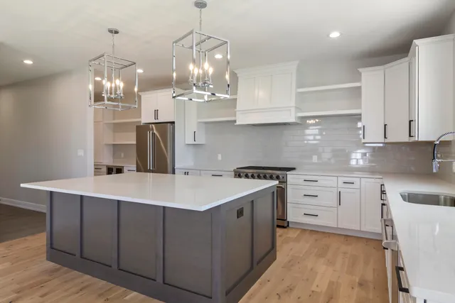a kitchen with kitchen island granite countertop stainless steel appliances a sink stove and white cabinets