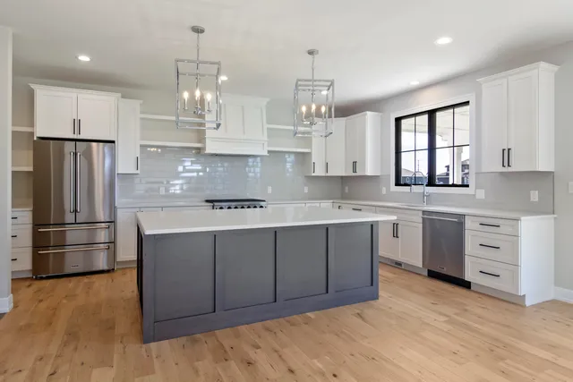 a kitchen with kitchen island granite countertop a stove a sink a refrigerator and cabinets