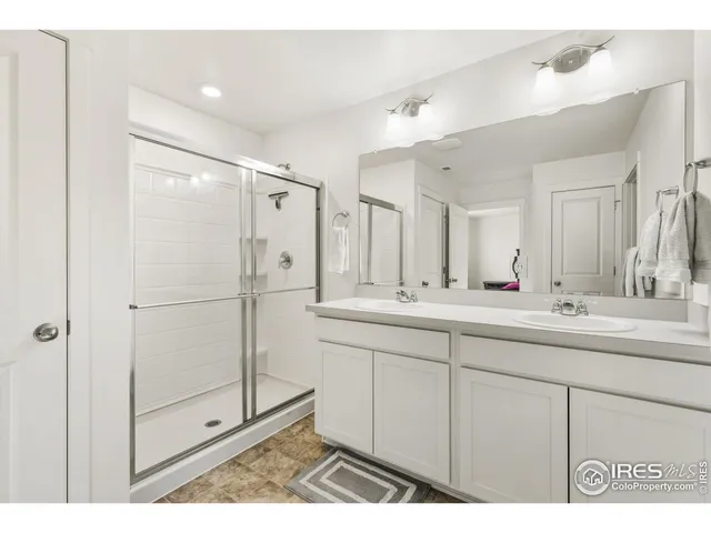 a bathroom with a double vanity sink mirror and shower