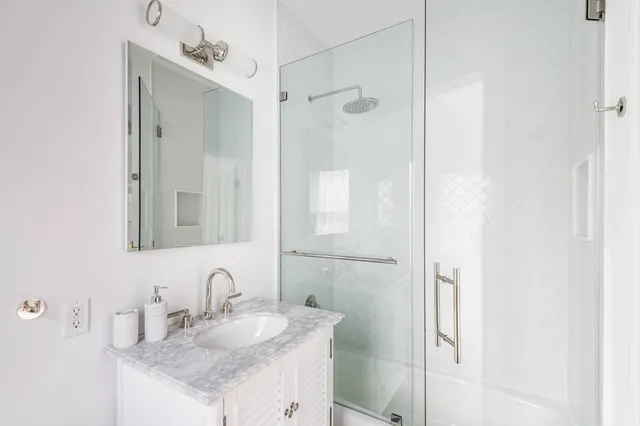 a bathroom with a granite countertop shower sink and mirror