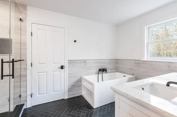 a bathroom with a white tub a sink and a window