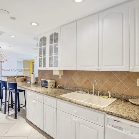 a kitchen with granite countertop white cabinets and sink