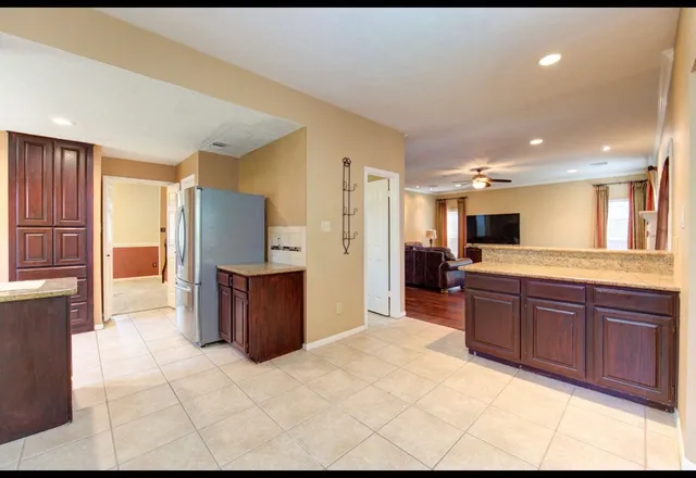 a large kitchen with stainless steel appliances kitchen island granite countertop a refrigerator and a sink