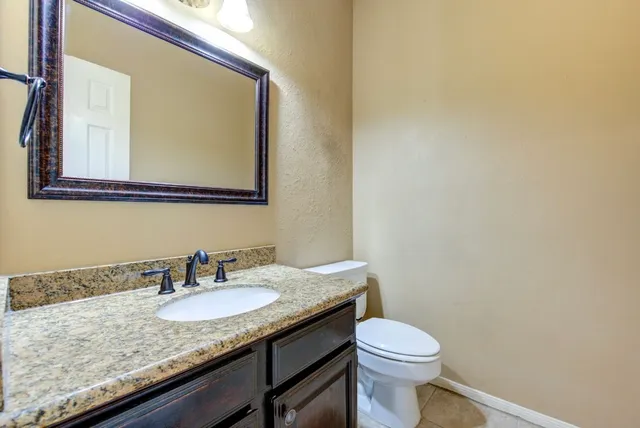 a bathroom with a granite countertop sink and a toilet