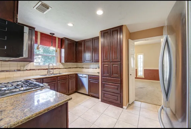 a kitchen with stainless steel appliances granite countertop a refrigerator and a stove