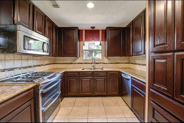 a kitchen with stainless steel appliances granite countertop wooden cabinets a stove top oven a sink and dishwasher