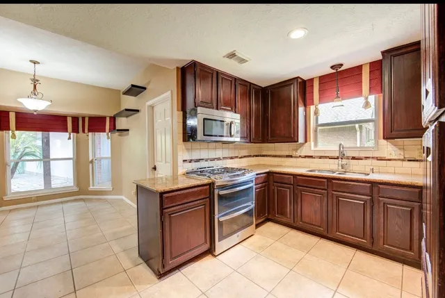a kitchen with stainless steel appliances granite countertop wooden cabinets a sink and dishwasher