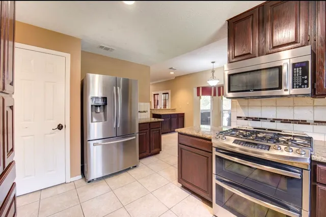 a kitchen with stainless steel appliances granite countertop a stove microwave and refrigerator